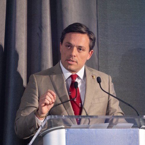 A photo of Carlos A. Lejneiks at a podium.